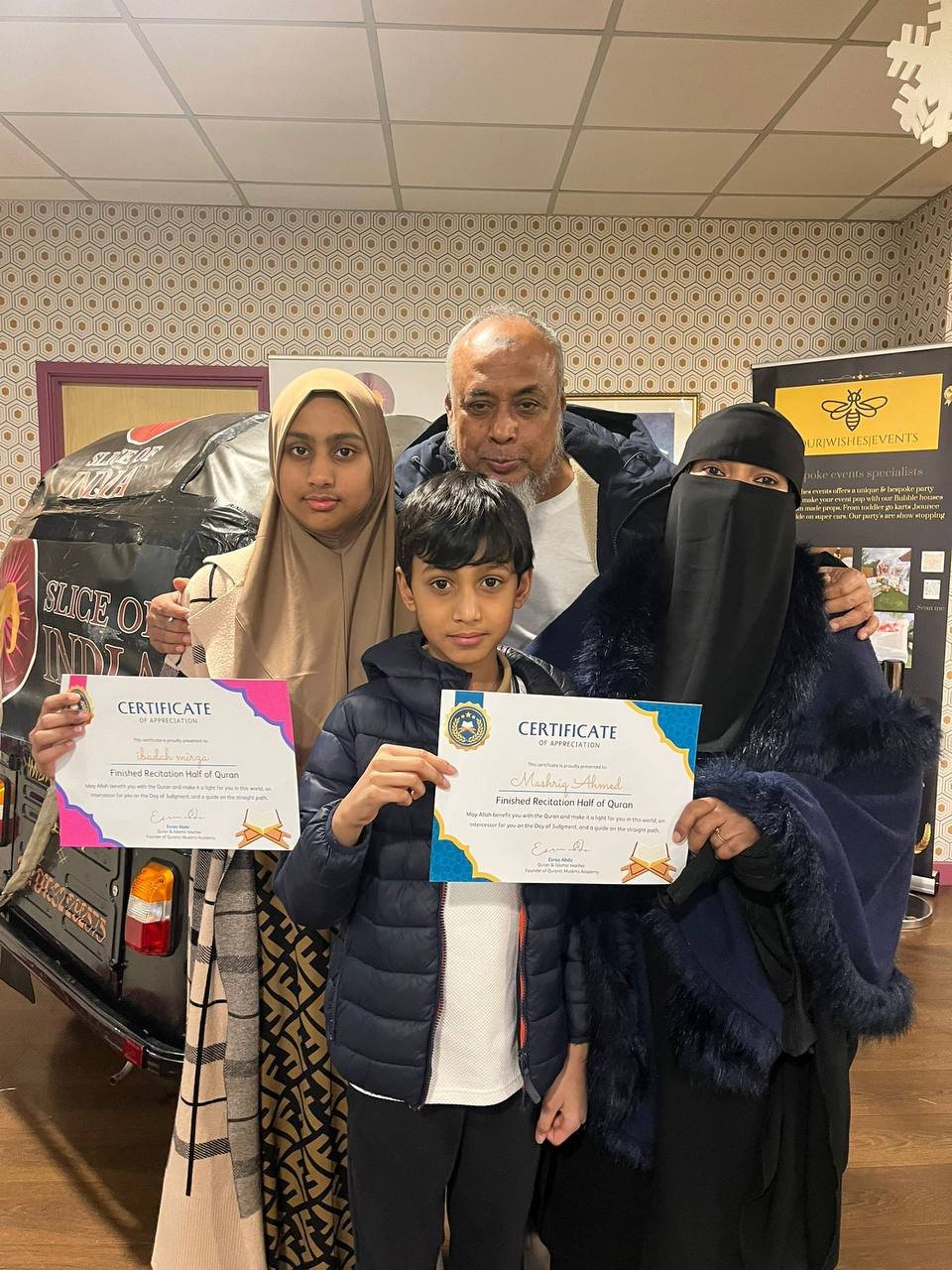 A proud family celebrating their children's Quran milestone