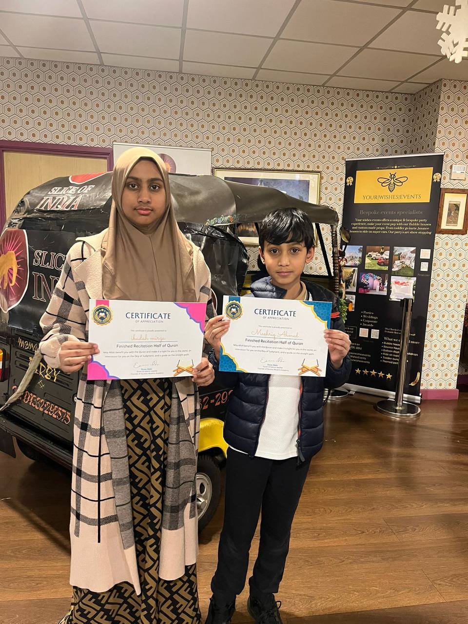 Two students with their certificates for completing half of the Quran